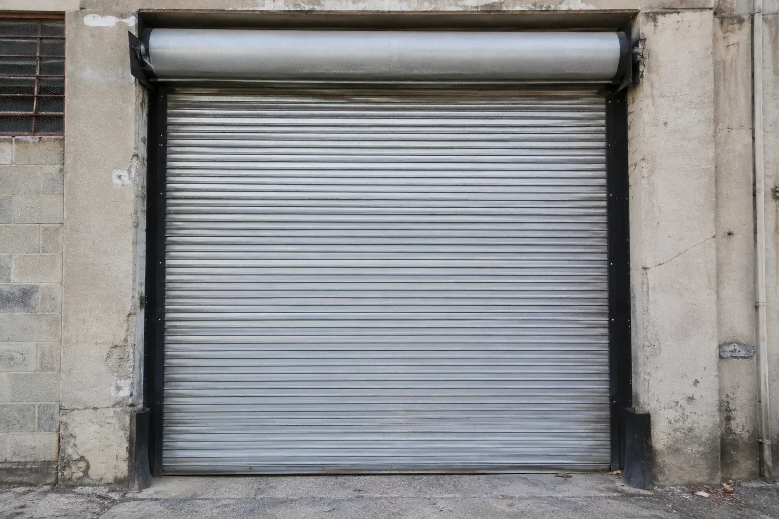 Closed metal rolling shutter in a weathered warehouse opening. — Commercial Rolling Door Repair, Vaughan
